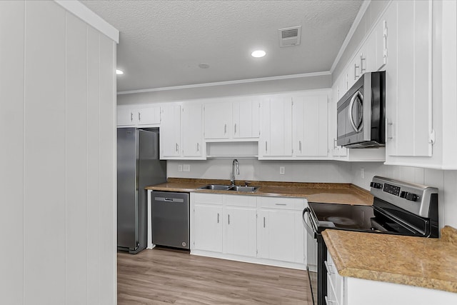 kitchen featuring a textured ceiling, a sink, stainless steel appliances, white cabinetry, and visible vents