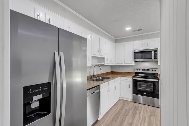 kitchen with crown molding, visible vents, appliances with stainless steel finishes, and a sink