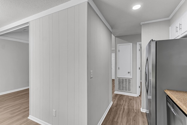 hall featuring light wood-type flooring, baseboards, and visible vents