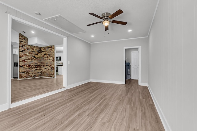 interior space with attic access, wood finished floors, crown molding, and ceiling fan