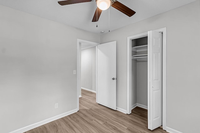unfurnished bedroom with baseboards, a ceiling fan, wood finished floors, and a closet