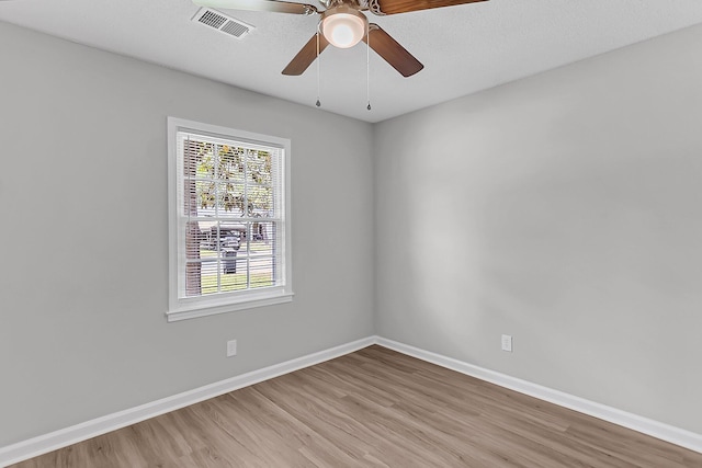 spare room featuring light wood finished floors, baseboards, ceiling fan, and visible vents