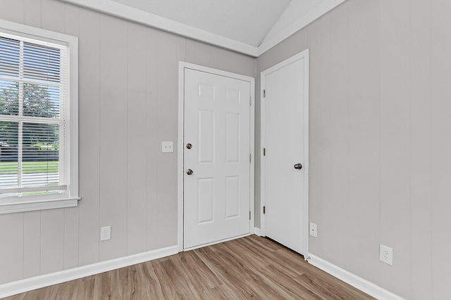 foyer featuring baseboards, vaulted ceiling, and wood finished floors