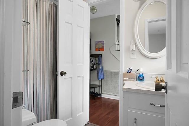 bathroom featuring hardwood / wood-style floors, vanity with extensive cabinet space, and toilet