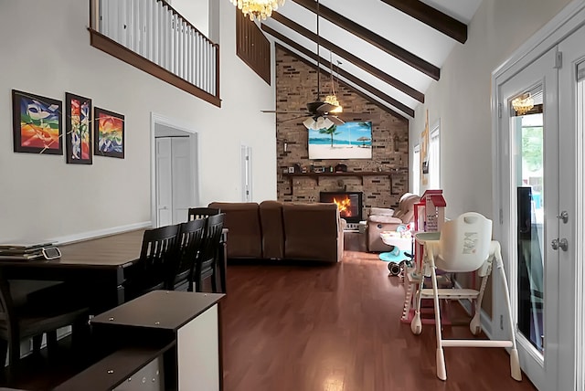 living room featuring high vaulted ceiling, hardwood / wood-style floors, beam ceiling, a stone fireplace, and ceiling fan