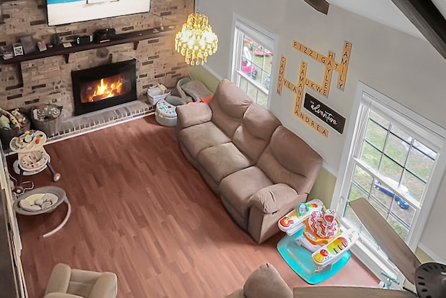 unfurnished living room featuring wood-type flooring, brick wall, a chandelier, and a fireplace