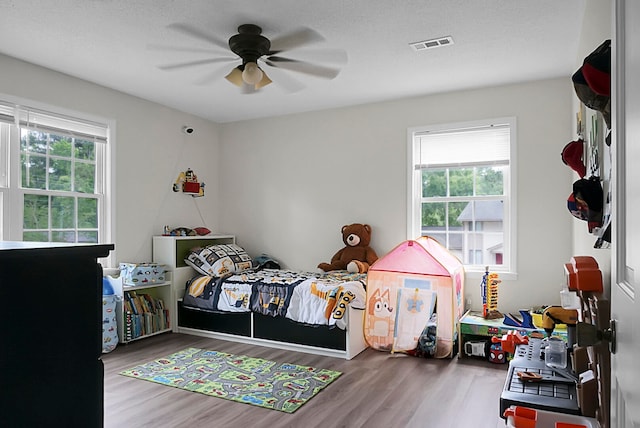 bedroom featuring wood-type flooring, ceiling fan, and multiple windows