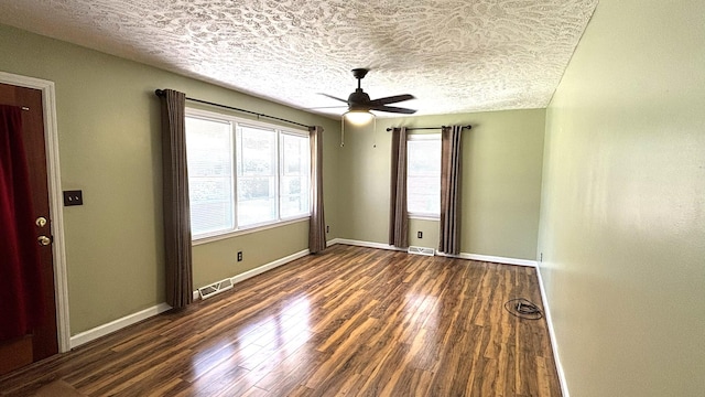 unfurnished room with a ceiling fan, visible vents, baseboards, a textured ceiling, and wood finished floors