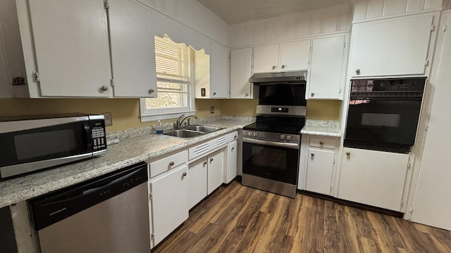 kitchen featuring a sink, appliances with stainless steel finishes, light countertops, under cabinet range hood, and dark wood finished floors