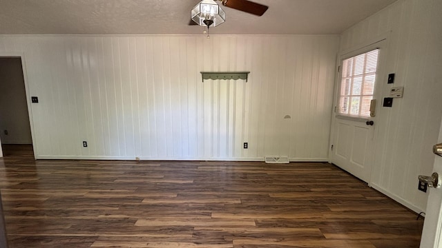 unfurnished room with baseboards, visible vents, ceiling fan, and dark wood finished floors