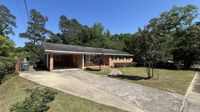 ranch-style home featuring brick siding, a carport, a front lawn, and driveway