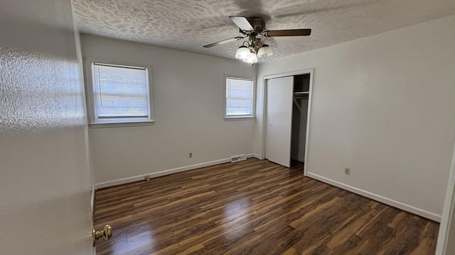 unfurnished bedroom with visible vents, a closet, baseboards, dark wood-style flooring, and a ceiling fan