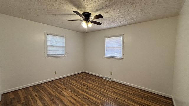 spare room featuring dark wood-style floors, baseboards, a healthy amount of sunlight, and a textured ceiling