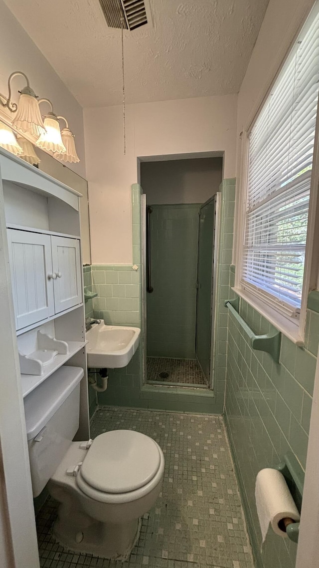 bathroom with visible vents, a stall shower, toilet, tile walls, and tile patterned flooring