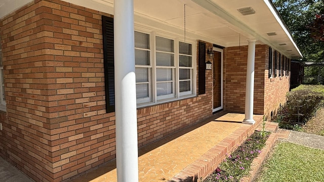 view of side of property featuring covered porch and brick siding