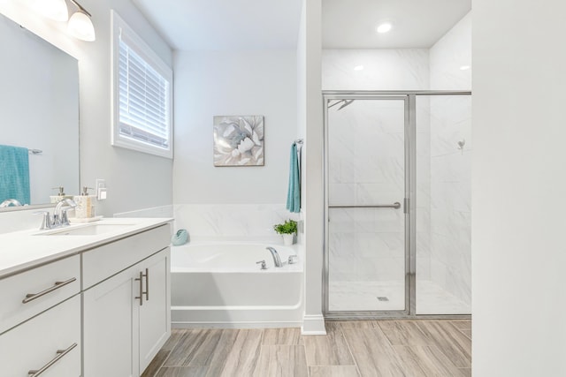 bathroom with a stall shower, a bath, and vanity