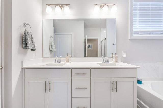 full bath featuring double vanity, a garden tub, a shower with door, and a sink