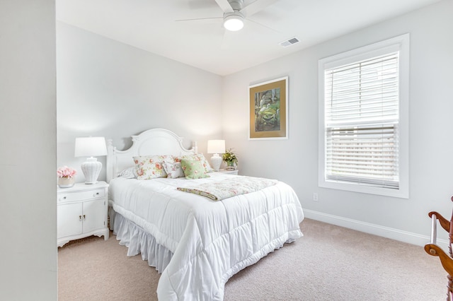 bedroom featuring visible vents, light colored carpet, a ceiling fan, and baseboards