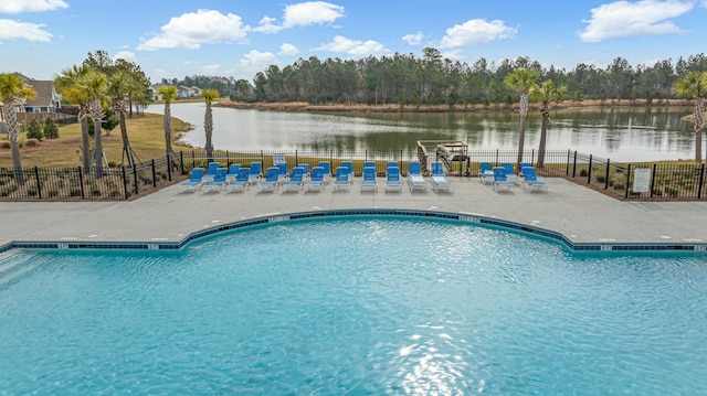 community pool featuring fence, a patio area, and a water view