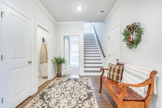 entryway featuring stairs, crown molding, wood finished floors, and visible vents