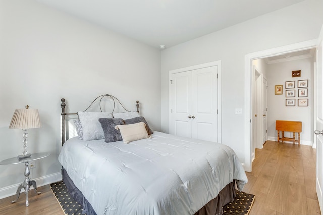 bedroom featuring a closet, light wood-type flooring, and baseboards