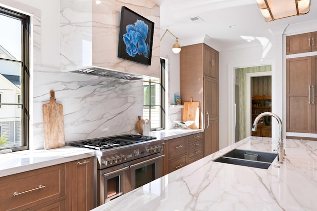 2538 Helmsman Rd, Johns Island, SC 29455 - kitchen featuring range with two ovens, brown cabinetry, a sink, backsplash, and wall chimney range hood