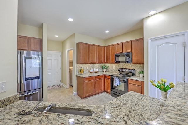 kitchen featuring a sink, black appliances, recessed lighting, light stone countertops, and backsplash