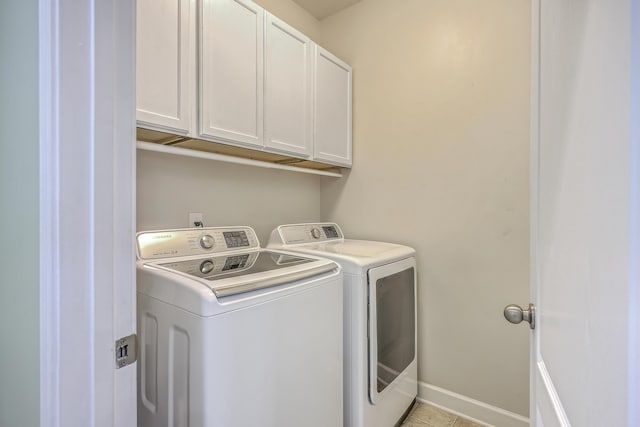 washroom featuring independent washer and dryer, light tile patterned floors, baseboards, and cabinet space