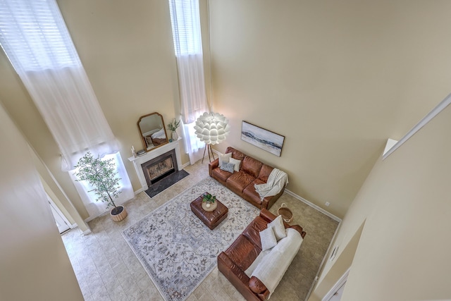 living room featuring a fireplace with flush hearth, a healthy amount of sunlight, and a towering ceiling