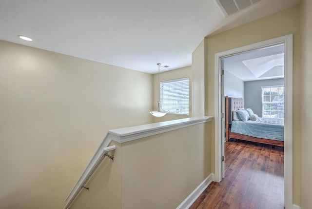 corridor featuring dark wood-type flooring, baseboards, an upstairs landing, and a wealth of natural light