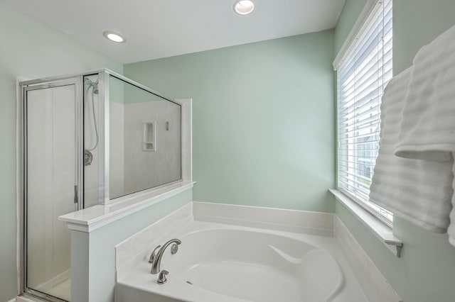 bathroom featuring a stall shower, a healthy amount of sunlight, and a garden tub