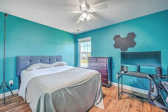 bedroom featuring ceiling fan, visible vents, baseboards, and wood finished floors