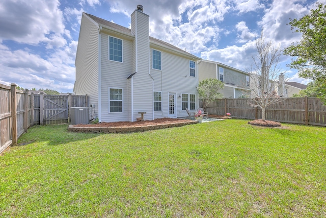 back of house featuring a yard, a fenced backyard, and a chimney