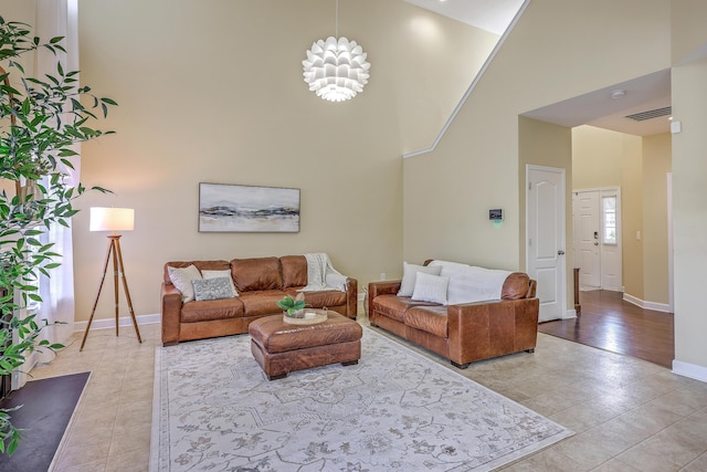living area with visible vents, baseboards, a high ceiling, and light tile patterned flooring