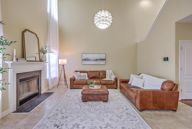 living area featuring a high ceiling, light tile patterned flooring, a fireplace, and baseboards
