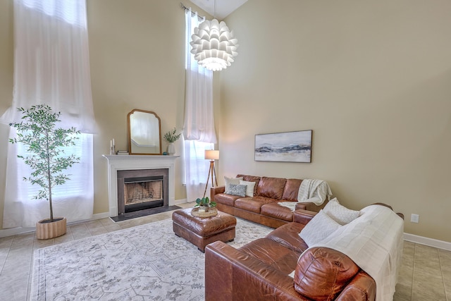 living area with tile patterned floors, a fireplace with flush hearth, a high ceiling, and baseboards