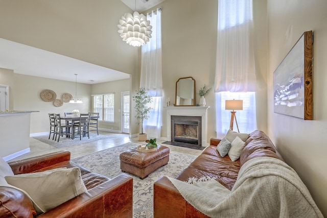 living room featuring baseboards, wood finished floors, a towering ceiling, and a fireplace with flush hearth