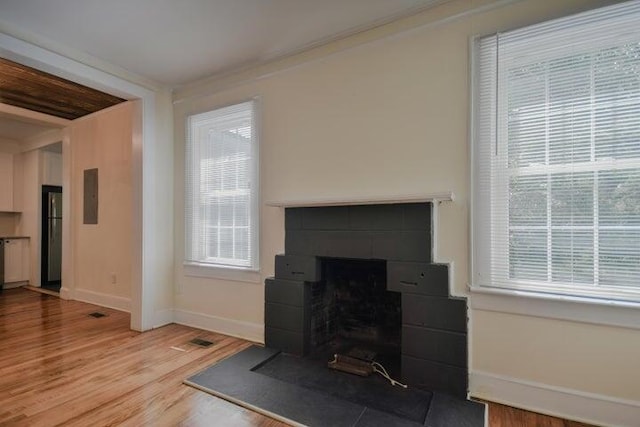 living room with light hardwood / wood-style flooring, a tile fireplace, electric panel, and ornamental molding