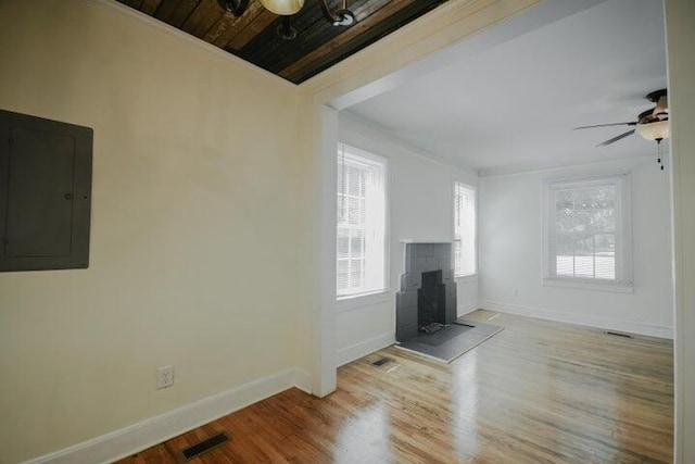 unfurnished living room featuring ceiling fan, electric panel, wood ceiling, a tile fireplace, and light hardwood / wood-style floors