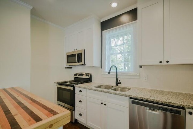 kitchen featuring sink, white cabinetry, stainless steel appliances, light stone countertops, and crown molding