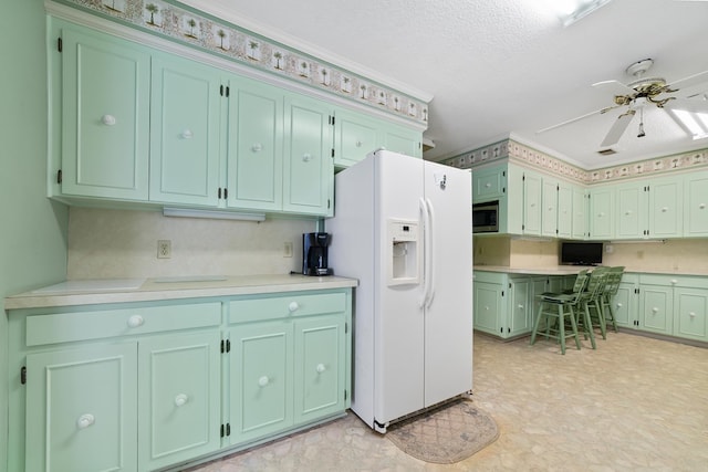 kitchen with ceiling fan, white refrigerator with ice dispenser, and a textured ceiling