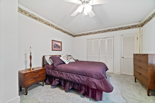 carpeted bedroom with crown molding, multiple closets, and ceiling fan