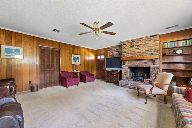 carpeted living room featuring a textured ceiling, a brick fireplace, wooden walls, and ceiling fan