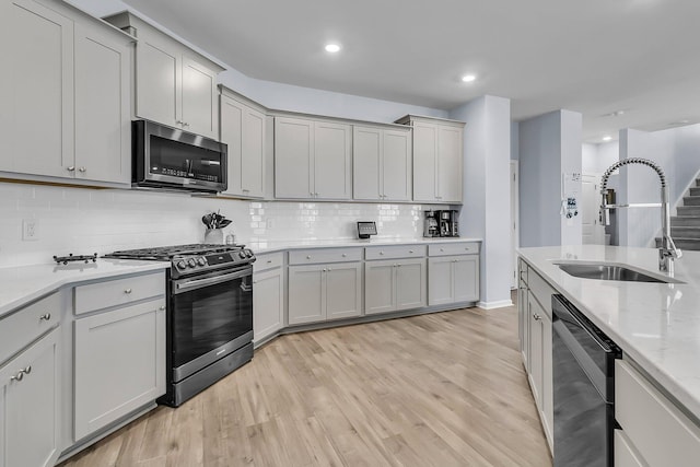 kitchen with backsplash, light wood-type flooring, recessed lighting, stainless steel appliances, and a sink