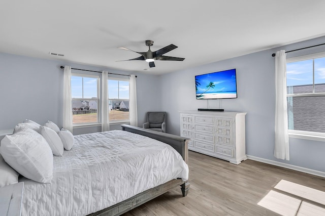 bedroom with ceiling fan, visible vents, baseboards, and wood finished floors