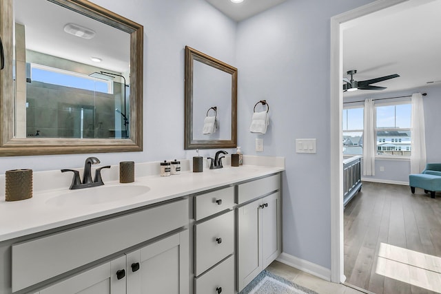 bathroom with ceiling fan, double vanity, a shower with shower door, and a sink