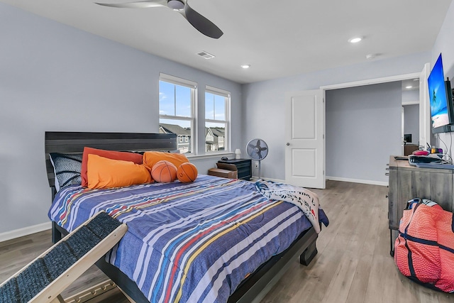 bedroom with ceiling fan, wood finished floors, visible vents, and baseboards