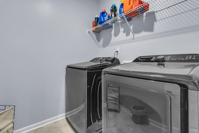 washroom featuring baseboards, washing machine and dryer, and laundry area