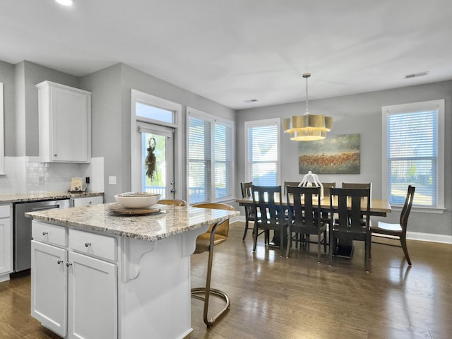 kitchen featuring pendant lighting, white cabinetry, dark hardwood / wood-style floors, a center island, and stainless steel dishwasher