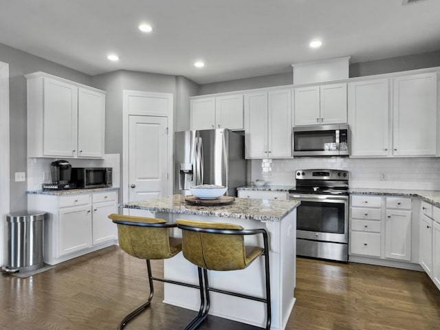 kitchen with a kitchen island, light stone countertops, appliances with stainless steel finishes, and white cabinets